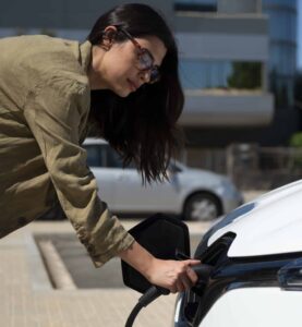 Femme qui recharge une voiture électrique avec M Solaire Energie